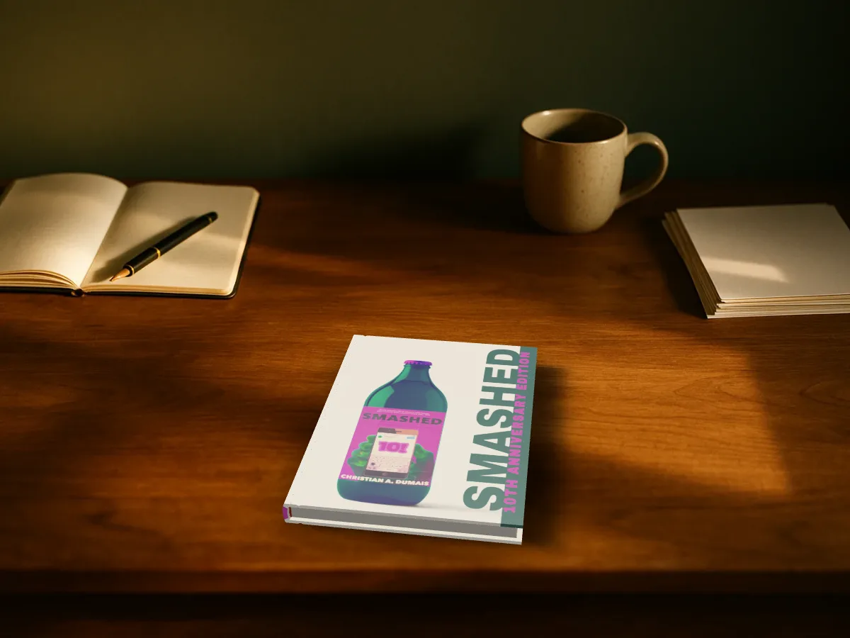 Smashed as a hardback lying on a wooden writer's desk next to a notebook and a mug