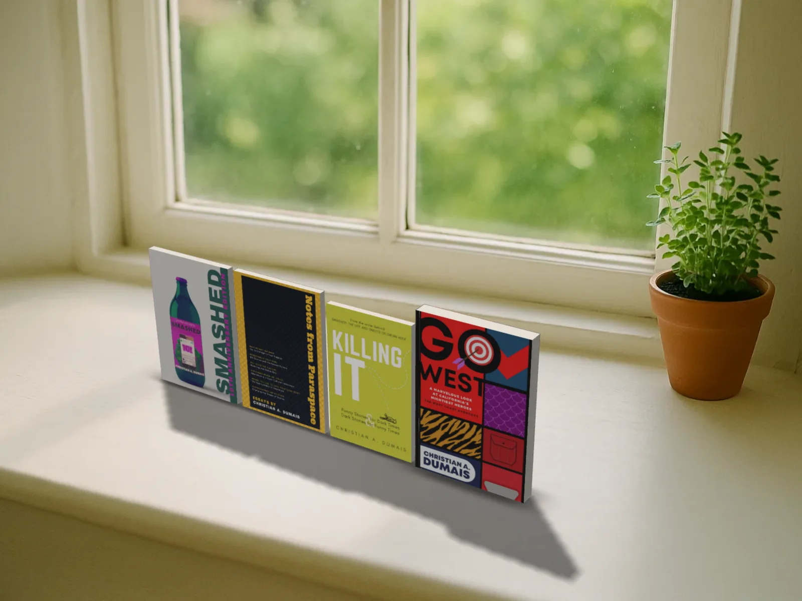 Four paperbacks standing side by side on a sunny white windowsill
