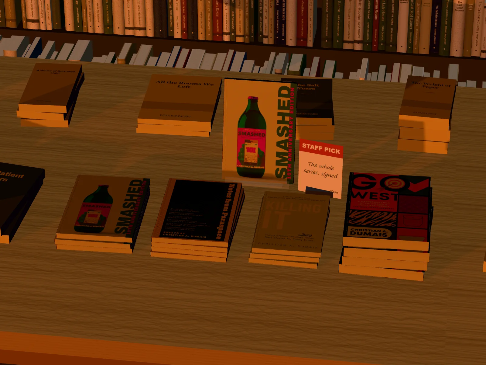 A pile of each of four books across the front of a new releases table, Smashed on a clear stand behind with a staff pick card
